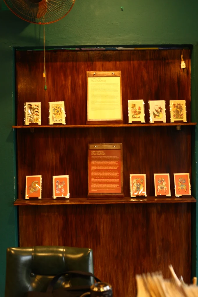 Wooden shelves displaying framed art cards and folk paintings