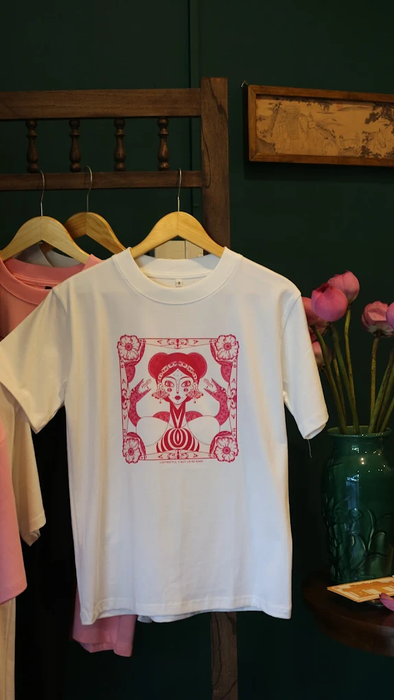 A white t-shirt with red artwork hanging in the art souvenir shop